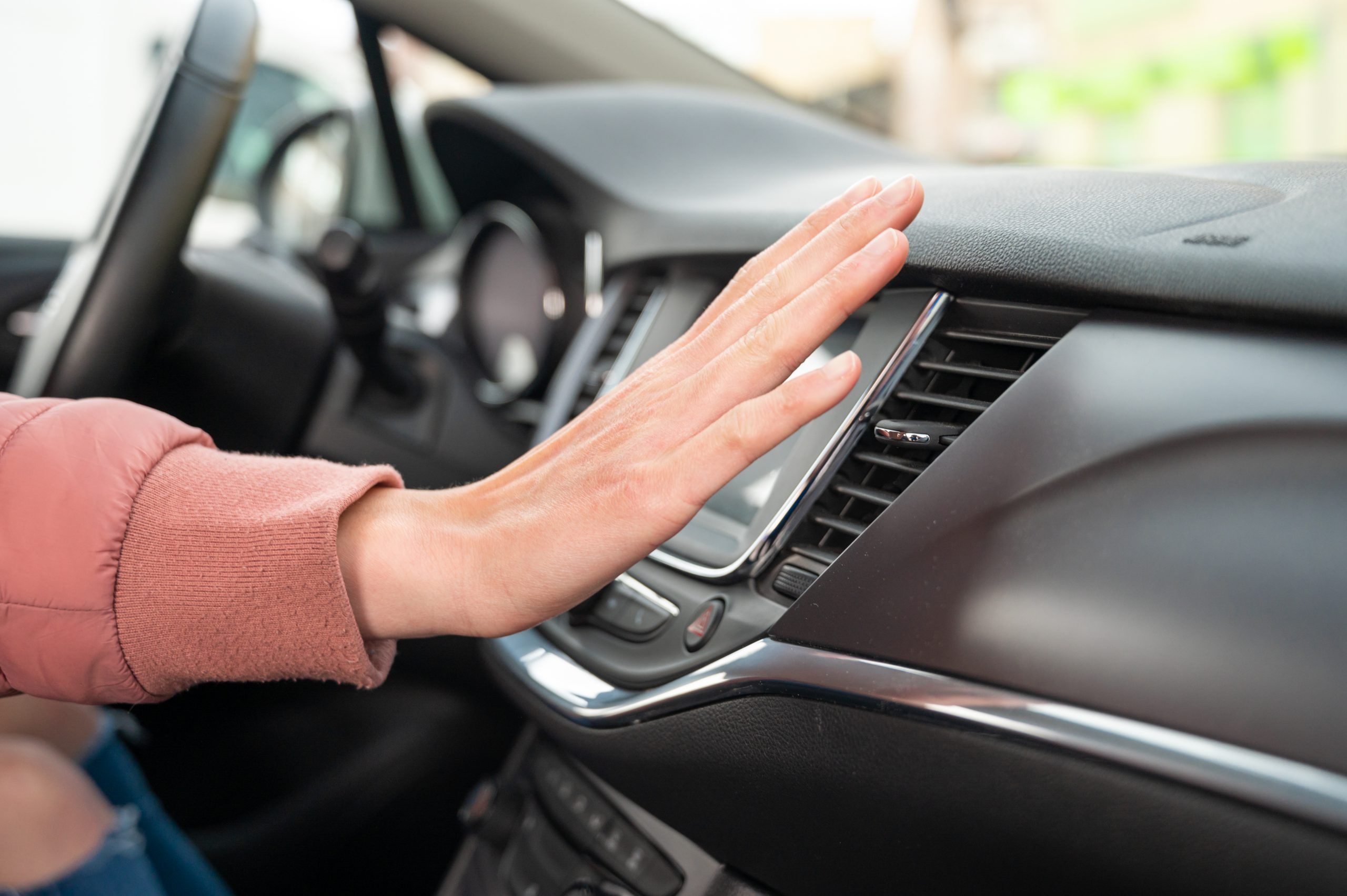 Woman using hand palm in front of AC vents to feel the speed and temperature of airflow during summer heat.
